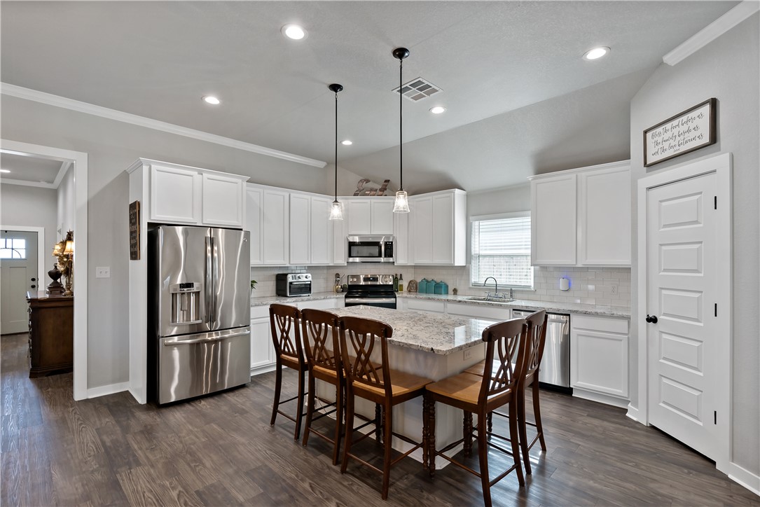 3161 Normandy Way Bryan, TX 77808 - Photo 9 of 27 a kitchen with stainless steel appliances a dining table chairs refrigerator and microwave