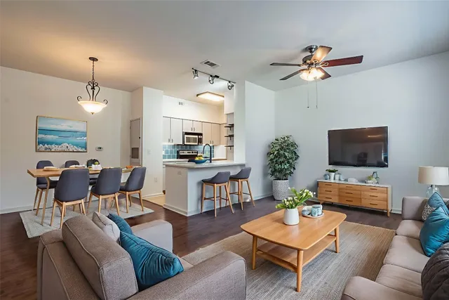 a living room with furniture kitchen view and a wooden floor