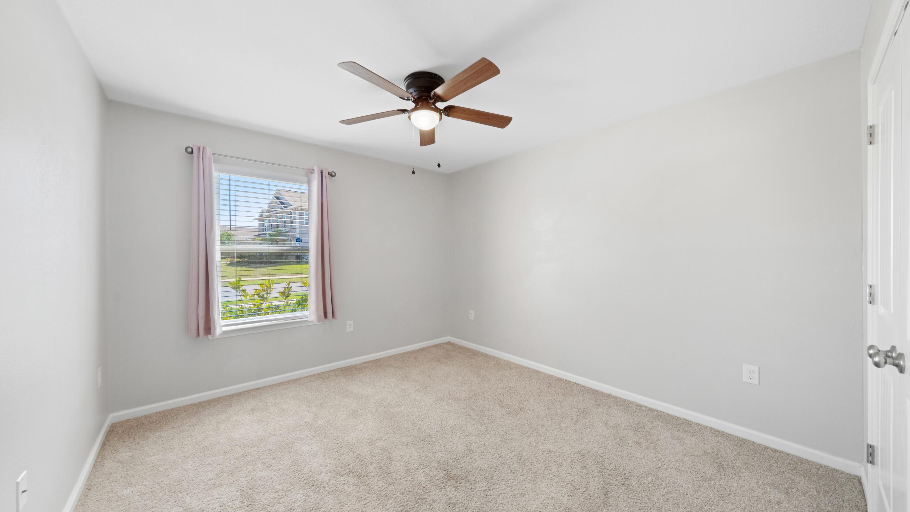 3927 Alva Thomas Road Panama City, FL 32404 - Photo 21 of 46 an empty room with windows and ceiling fan