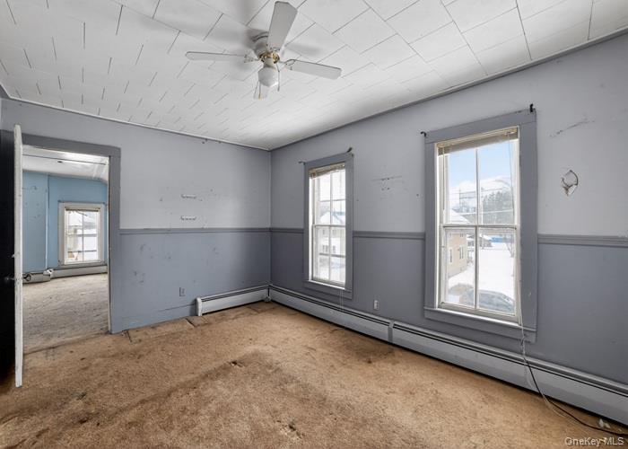 62 George Street Owego, NY 13827 - Photo 14 of 21 Empty room featuring a baseboard radiator, a ceiling fan, and carpet floors