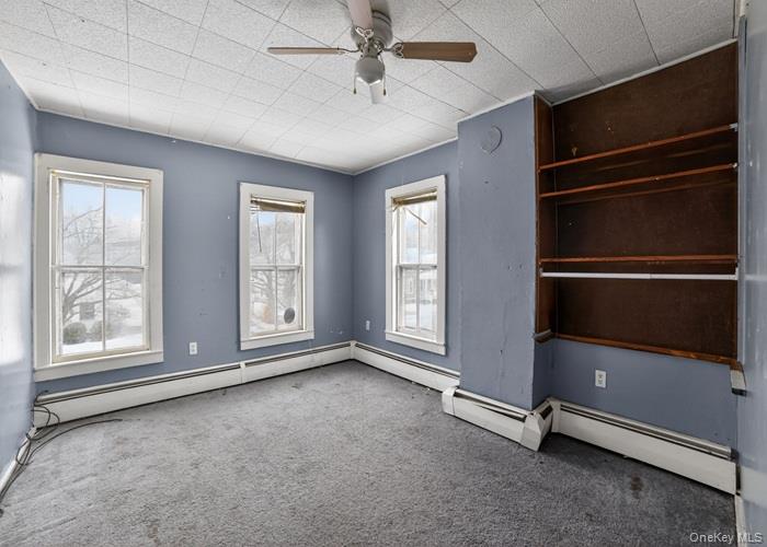 62 George Street Owego, NY 13827 - Photo 15 of 21 Carpeted spare room with ceiling fan, a baseboard radiator, and healthy amount of natural light