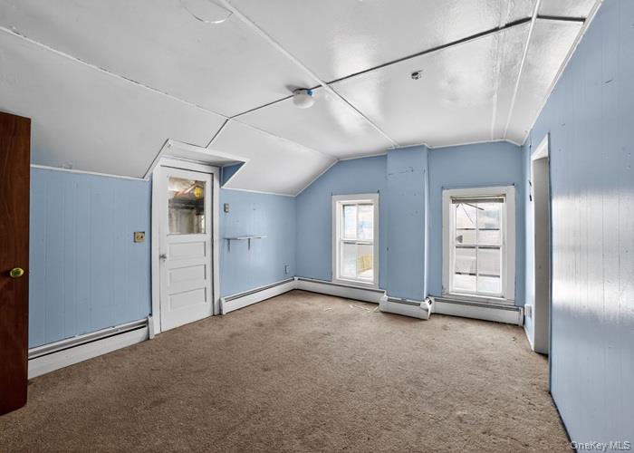 62 George Street Owego, NY 13827 - Photo 17 of 21 Additional living space featuring vaulted ceiling, a baseboard heating unit, carpet floors, and wooden walls