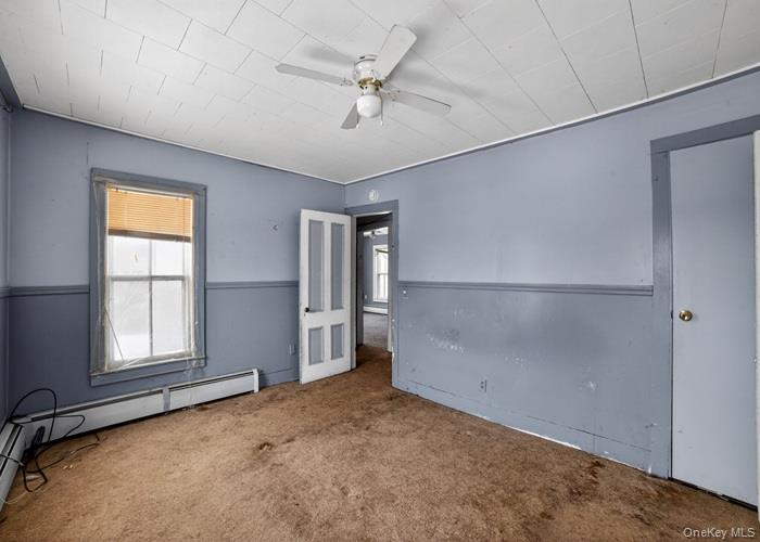 62 George Street Owego, NY 13827 - Photo 18 of 21 Spare room featuring carpet floors, a ceiling fan, and a baseboard radiator