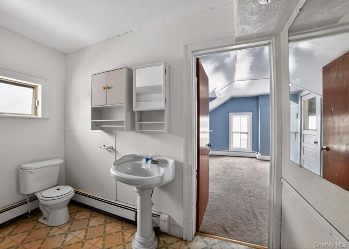 62 George Street Owego, NY 13827 - Photo 21 of 21 Bathroom with light carpet, a baseboard heating unit, vaulted ceiling, and light floors