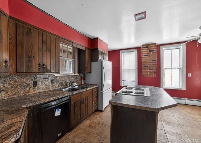 62 George Street Owego, NY 13827 - Photo 10 of 21 Kitchen with dark brown cabinetry, a kitchen island, dark countertops, white appliances, and backsplash