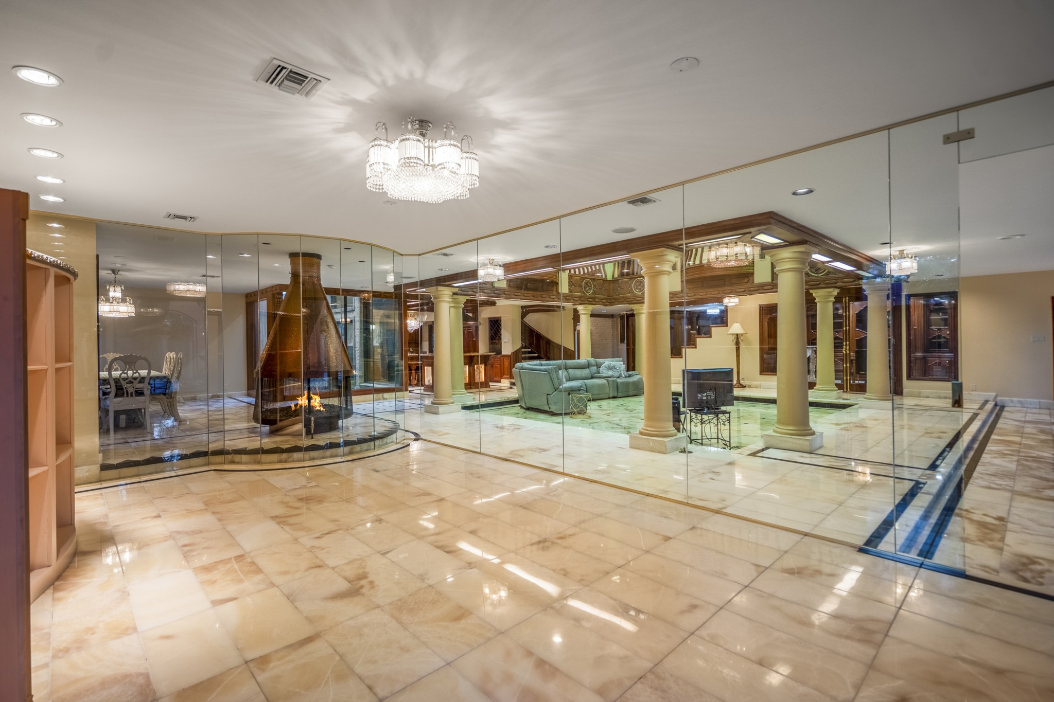 6535 Buffalo Speedway Houston, TX 77005 - Photo 19 of 40 Expand your entertaining into this elegant, glass-enclosed formal living room, complete with a beautiful chandelier, custom-built display shelves, and artfully tiled flooring that adds warmth and character.