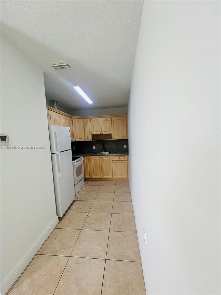 2185 Northwest 16th Terrace, Unit 16 Miami, FL 33125 - Photo 5 of 14 a kitchen with white cabinets and refrigerator