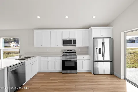 a kitchen with granite countertop a refrigerator stove and wooden floor
