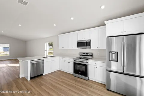 a kitchen with stainless steel appliances white cabinets and a stove a sink