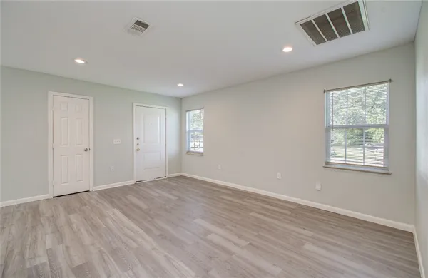 an empty room with wooden floor and windows