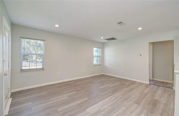an empty room with wooden floor and windows