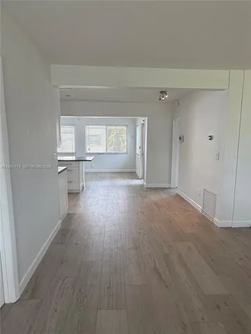 a view of empty room with wooden floor and window
