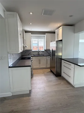 a kitchen with stainless steel appliances granite countertop a refrigerator and a sink