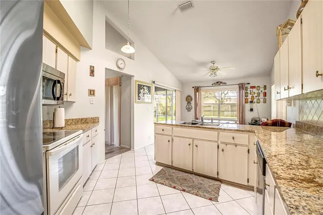 a large white kitchen with granite countertop a sink and dishwasher a stove top oven with wooden floor