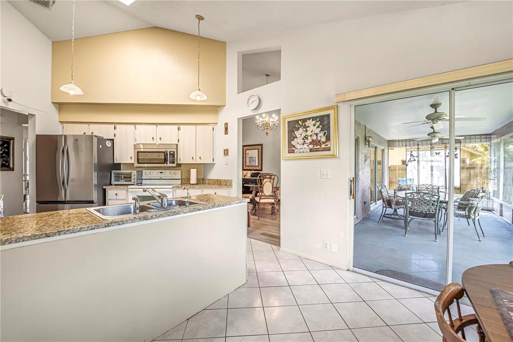 12196 Bluefield Street Spring Hill, FL 34609 - Photo 19 of 47 a kitchen with stainless steel appliances a refrigerator a stove top oven and a dining table view