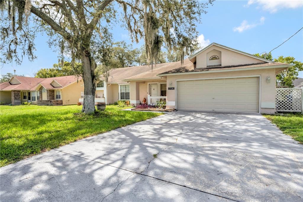 12196 Bluefield Street Spring Hill, FL 34609 - Photo 7 of 47 a front view of a house with a garden and trees