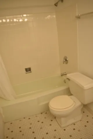 a white toilet sitting next to a bath tub and a shower