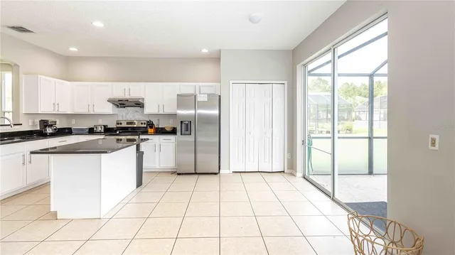 a kitchen with a refrigerator a stove top oven and white cabinets