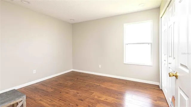 a view of an empty room with wooden floor and a window
