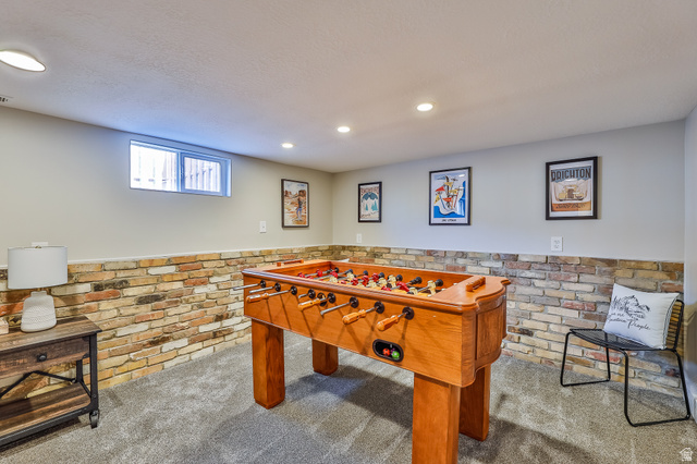 59 East 8680th Street South Sandy, UT 84070 - Photo 17 of 33 Finished interior space with a window, recessed lighting, carpet flooring, and a brick-finish accent wall