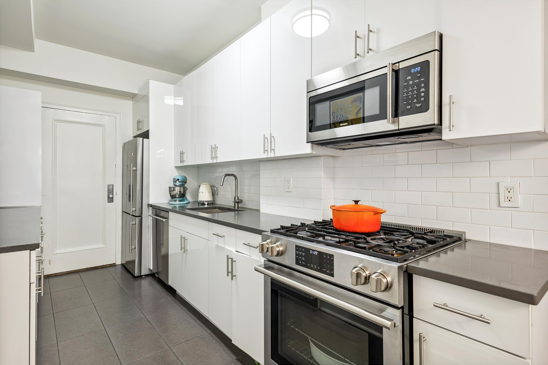 242 East 19th Street, Unit 2C Manhattan, NY 10003 - Photo 4 of 9 a kitchen with stainless steel appliances granite countertop a stove microwave and sink