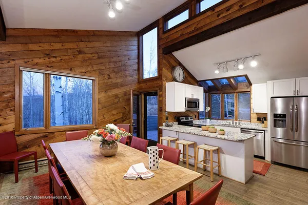 a room with stainless steel appliances kitchen island granite countertop a table chairs and a refrigerator