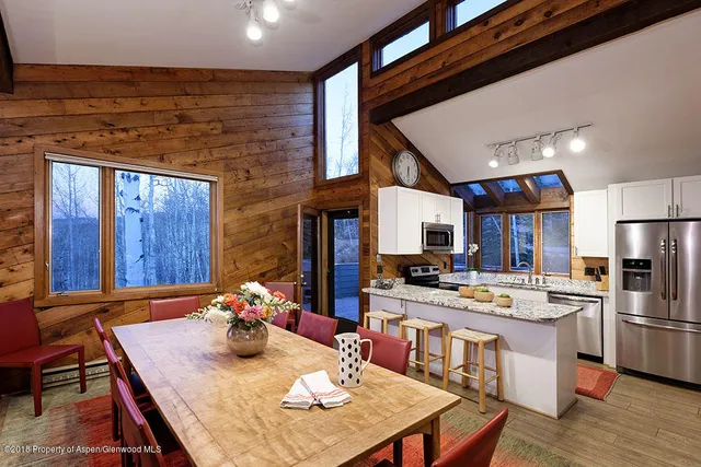 a room with stainless steel appliances kitchen island granite countertop a table chairs and a refrigerator