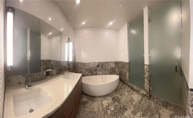 a bathroom with a granite countertop sink and a bathtub