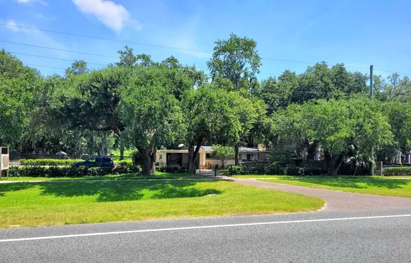 a front view of a house with a big yard and trees