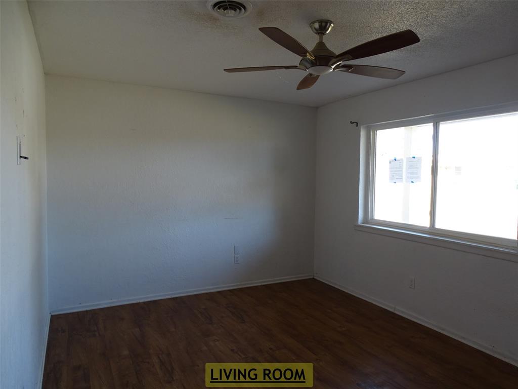 908 Brookside Street Sweetwater, TX 79556 - Photo 2 of 20 an empty room with a ceiling fan and window