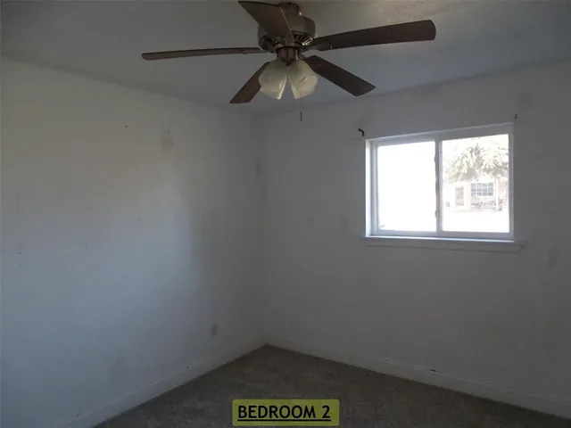 an empty room with a window and a fan