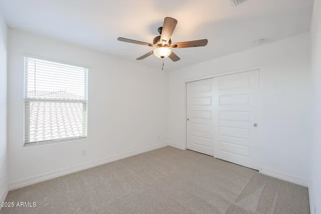 an empty room with a window and a fan