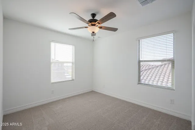 an empty room with windows and fan