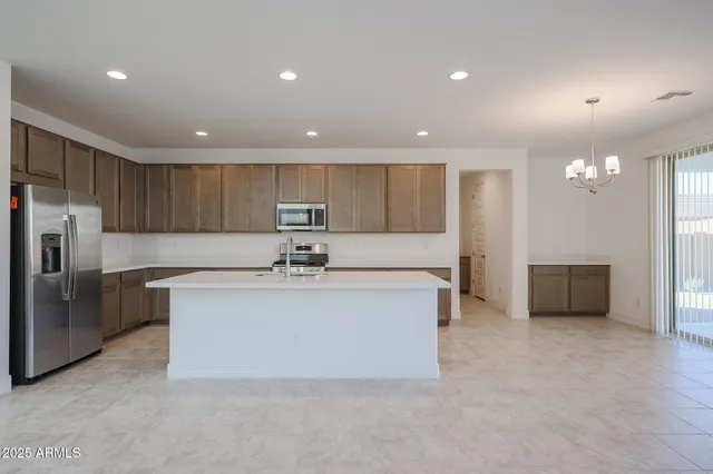 a large white kitchen with a refrigerator a counter top and a sink
