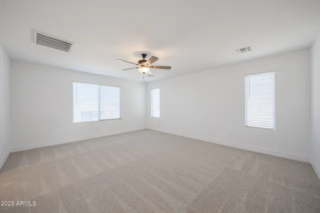 an empty room with windows and chandelier fan