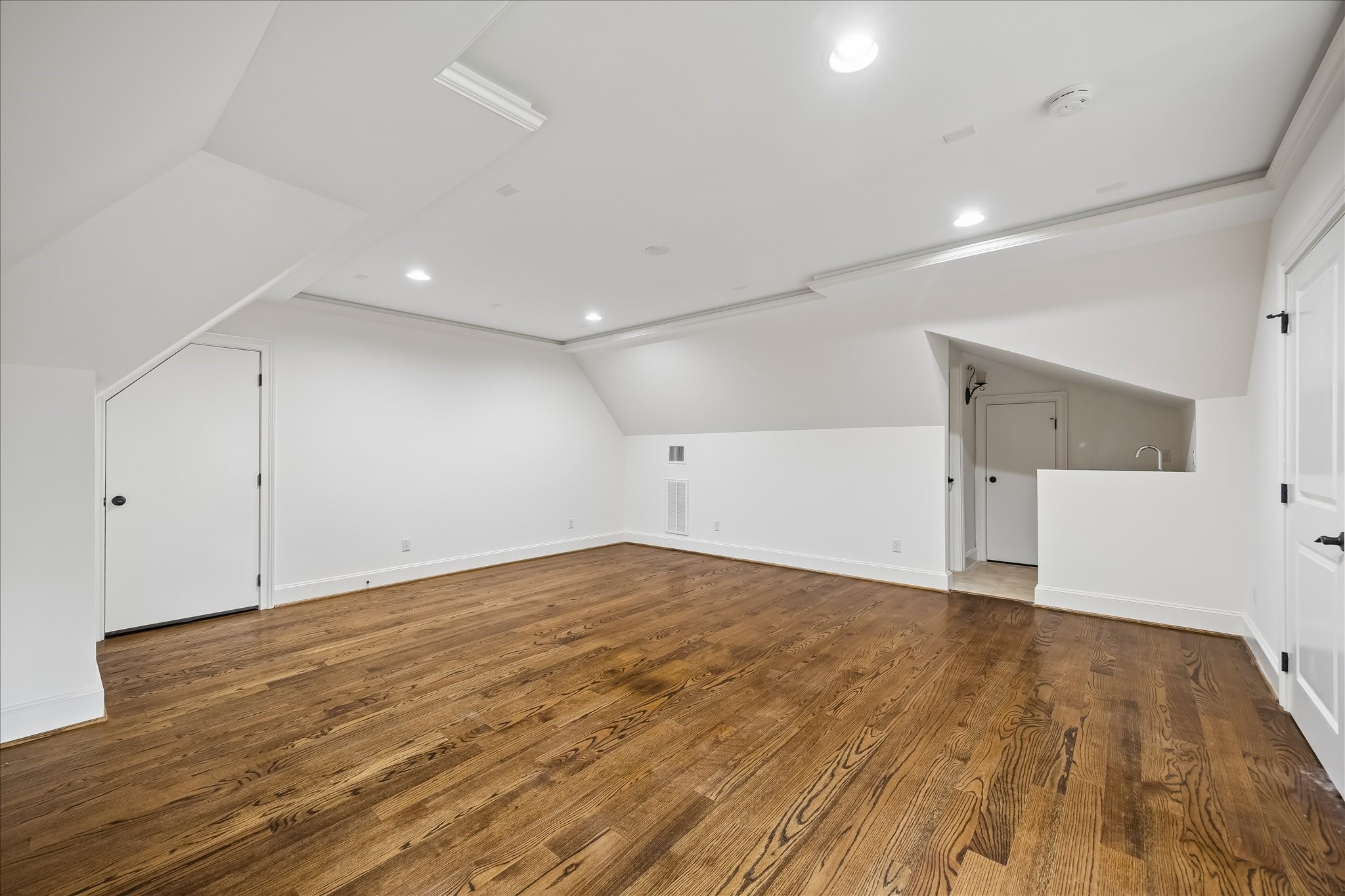 2246 Branard Street Houston, TX 77098 - Photo 36 of 40 A spacious third-floor retreat with hardwood floors, recessed lighting, wet bar with beverage fridge, and adjoining half bath—ideal for a game room, media space, gym, or guest lounge.