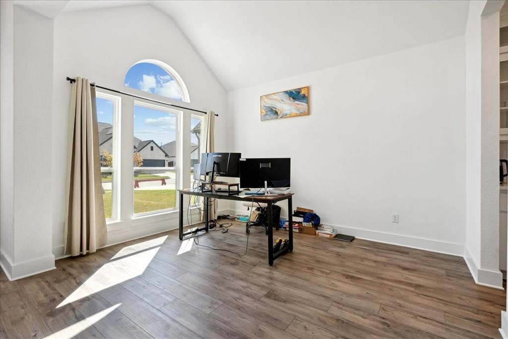1710 Highwood Road Forney, TX 75126 - Photo 14 of 25 Vaulted ceiling room featuring wood-finish flooring, white baseboards, and a large window array with an arched transom