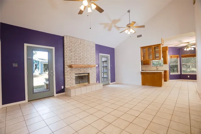 a view of a livingroom with a fireplace a chandelier a ceiling fan and windows