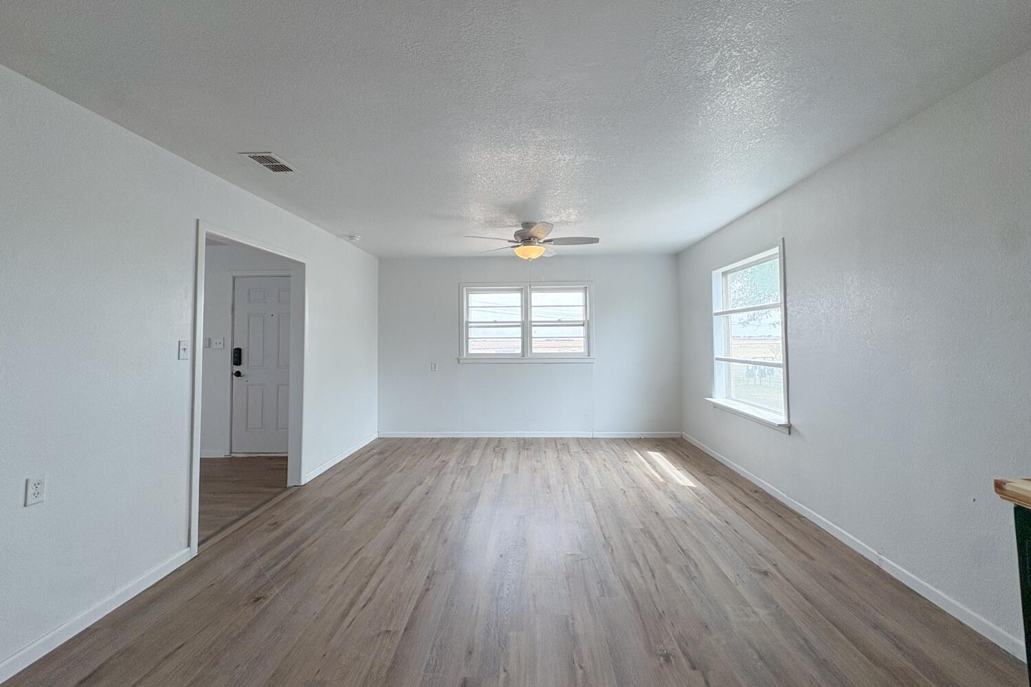 809 West 5th Street Wolfforth, TX 79382 - Photo 5 of 23 an empty room with wooden floor and windows