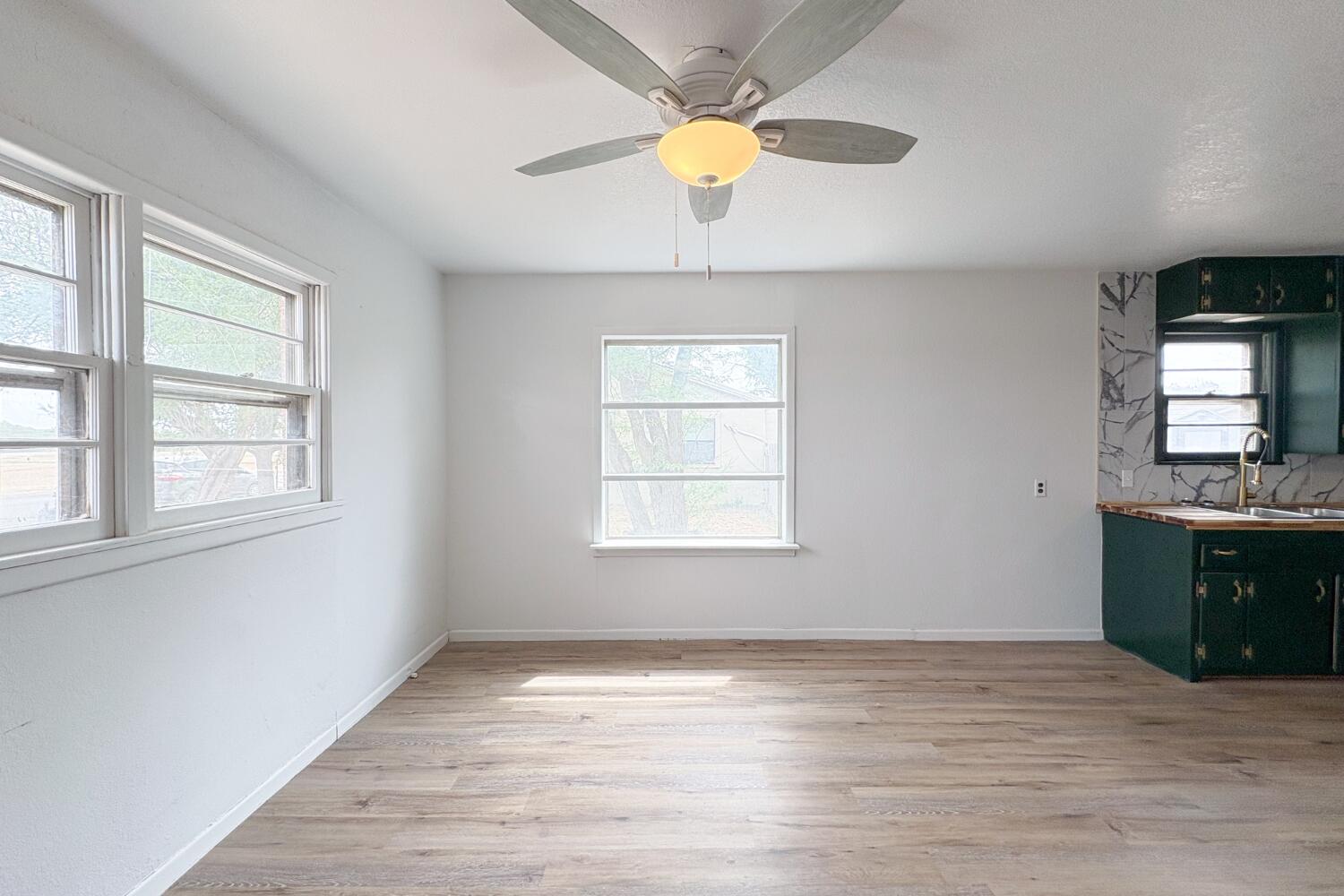 809 West 5th Street Wolfforth, TX 79382 - Photo 6 of 23 an empty room with wooden floor chandelier fan and windows