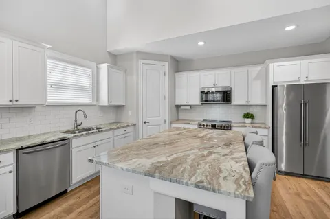a kitchen with granite countertop a sink stove refrigerator and cabinets