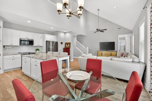 a living room with furniture kitchen view and a chandelier