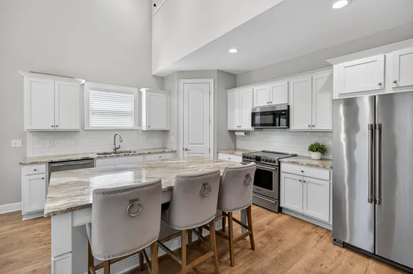 a kitchen with stainless steel appliances a white cabinets and a stove top oven