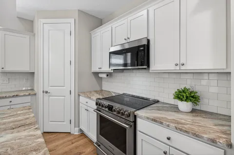 a kitchen with stainless steel appliances granite countertop white cabinets and a stove