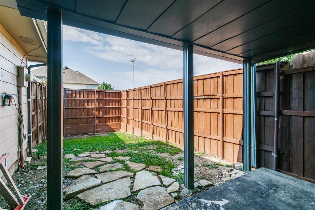 1712 East Peters Colony Road Carrollton, TX 75007 - Photo 24 of 25 Covered patio area opening to a fenced backyard with flagstone pavers and a grass patch