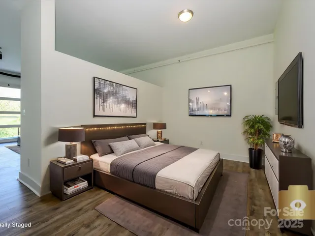 a bedroom with bed a couch and potted plant on the dresser