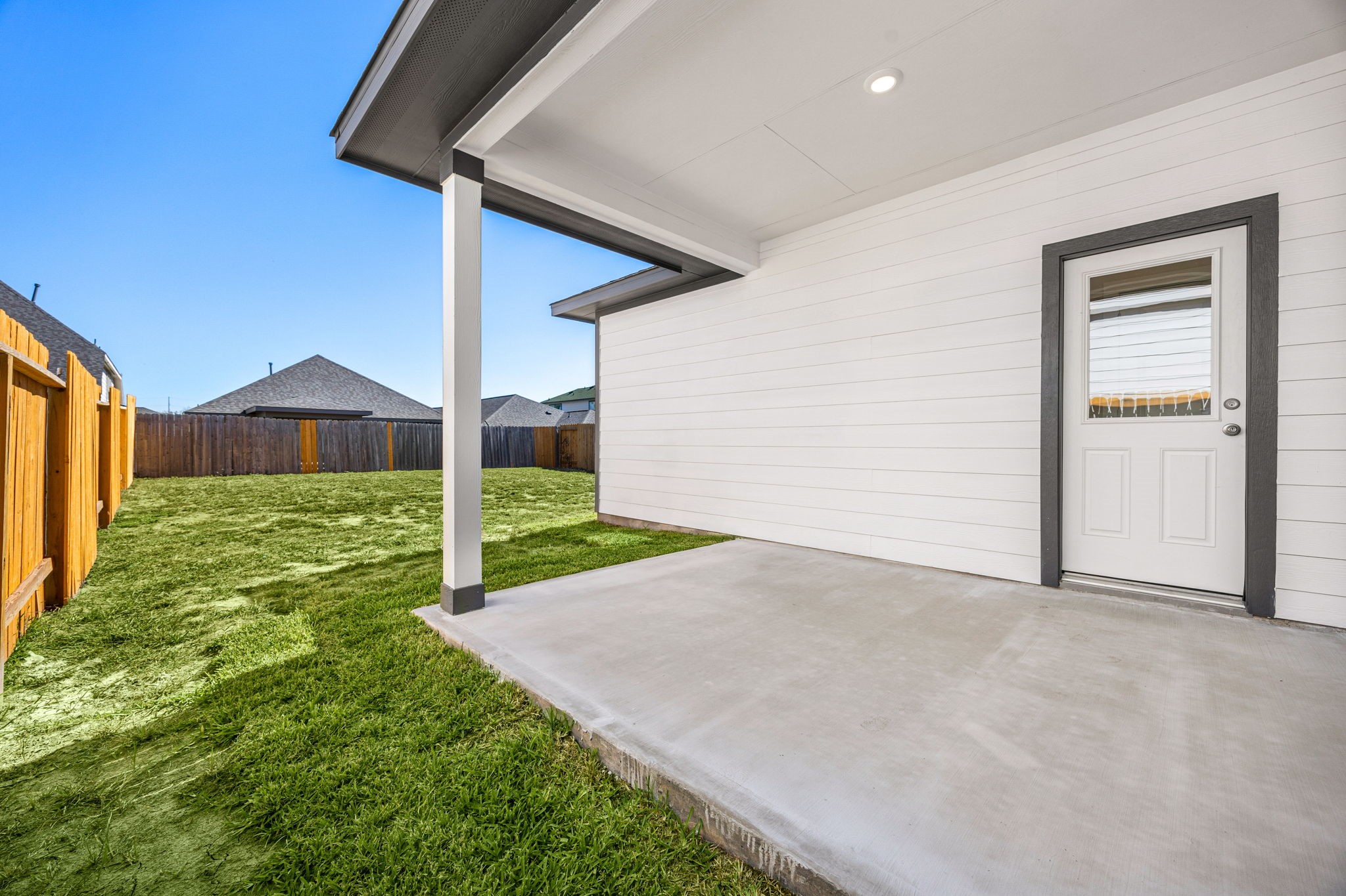 1128 Lilly Lane Bellville, TX 77418 - Photo 21 of 25 The inviting covered rear patio offers a seamless extension of indoor living to the outdoors. This spacious area features a durable concrete slab, perfect for outdoor furniture and entertaining.