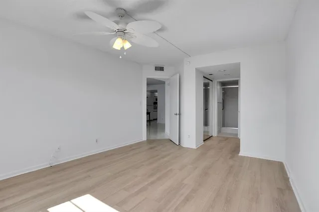 an empty room with wooden floor and a ceiling fan