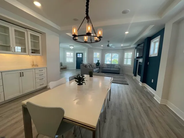 a view of a dining room and livingroom with furniture wooden floor a chandelier