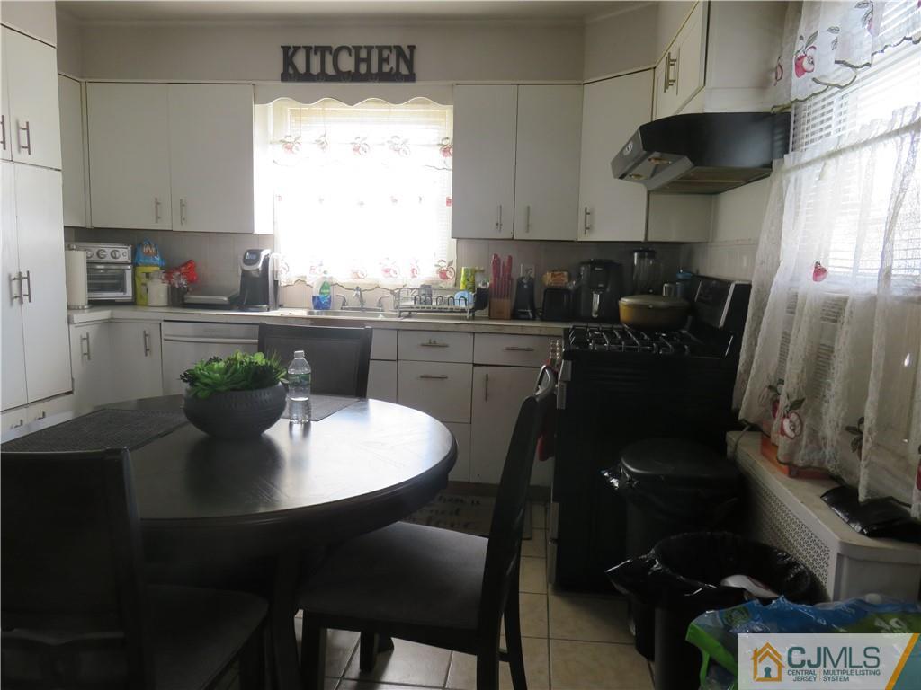 551 Colgate Avenue Perth Amboy, NJ 08861 - Photo 5 of 16 a kitchen with a table chairs stove and cabinets